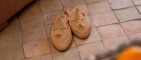 A pair of woven slippers on a tiled floor.