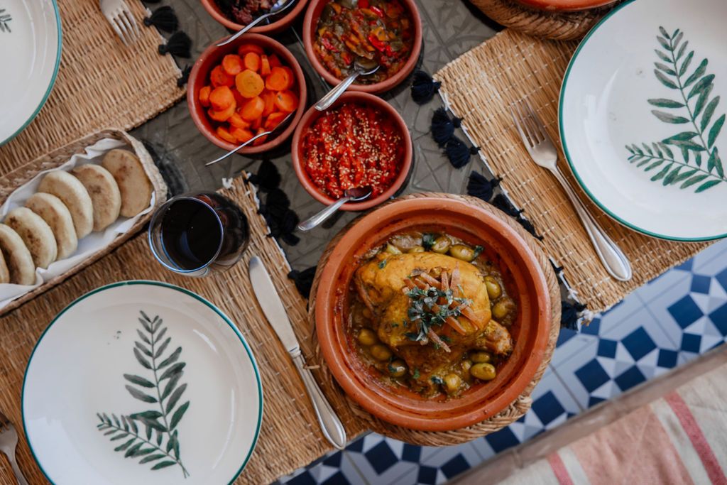 A table set with various dishes, including a large pot of stew, bowls of vegetables, and bread.