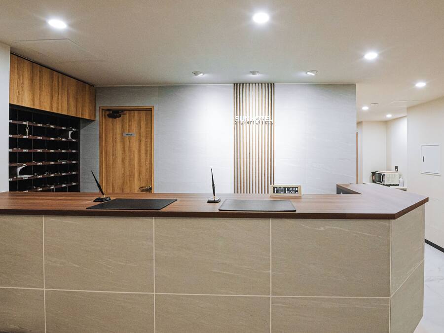 Un mostrador de recepción con paneles de madera y un reloj digital.