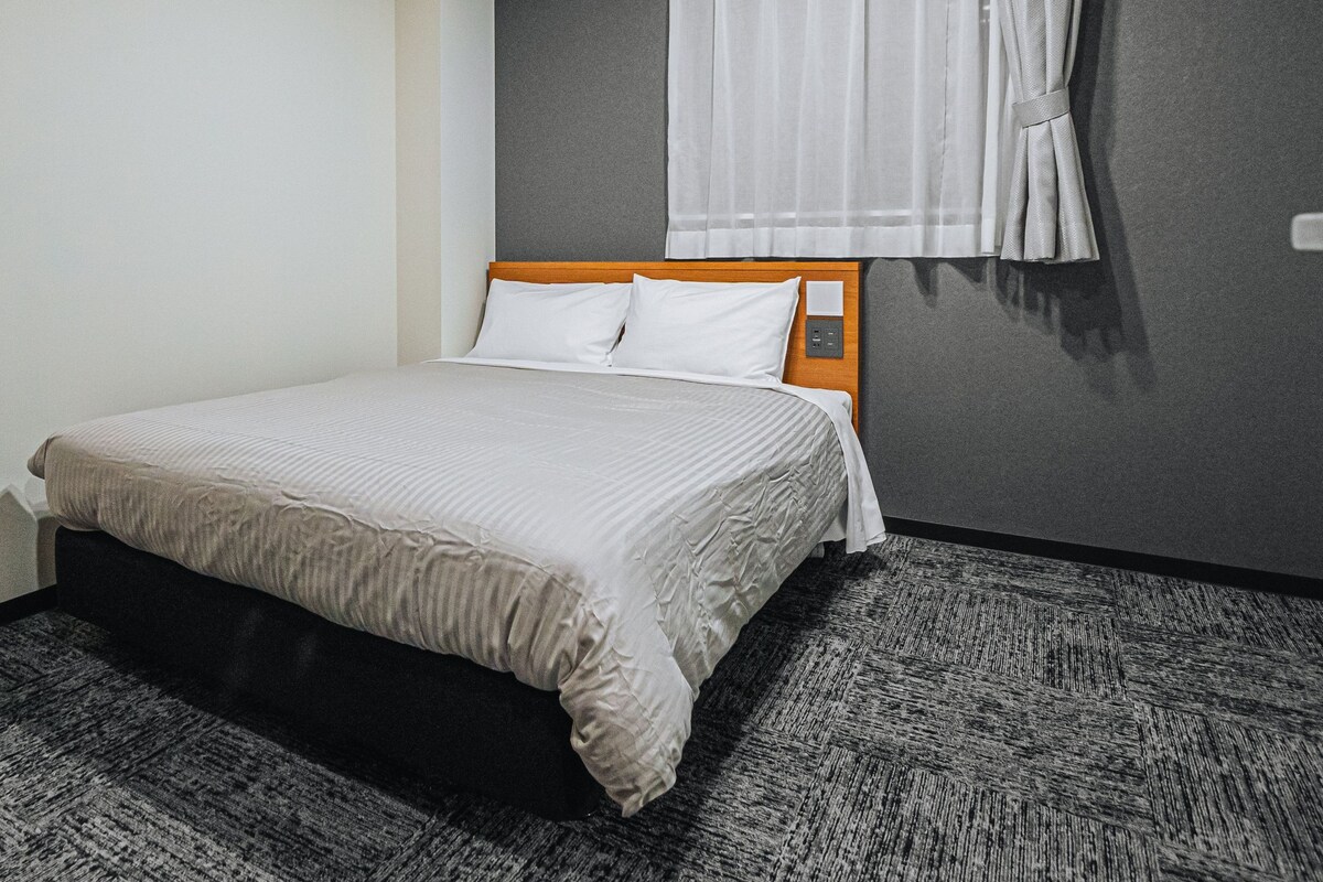 A hotel room with a bed, a desk, and a 'No Smoking' sign.
