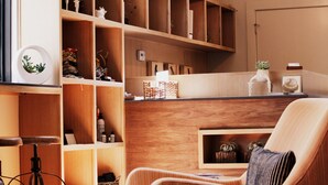 A cozy room with wooden shelving, a comfortable chair, and a desk area. - Heywood Hotel (Austin)