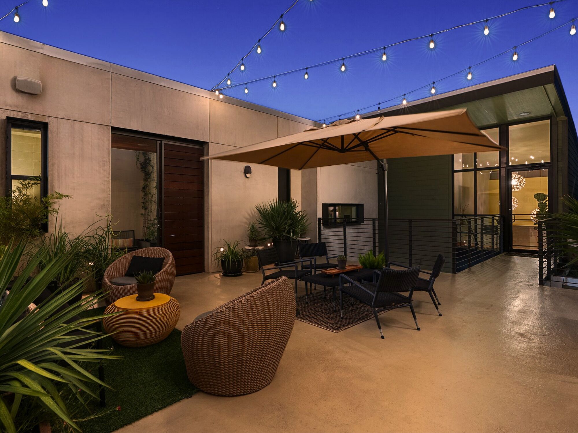 Eine Terrasse im Freien mit Sitzgelegenheiten, Blumentöpfen und Lichterketten.
