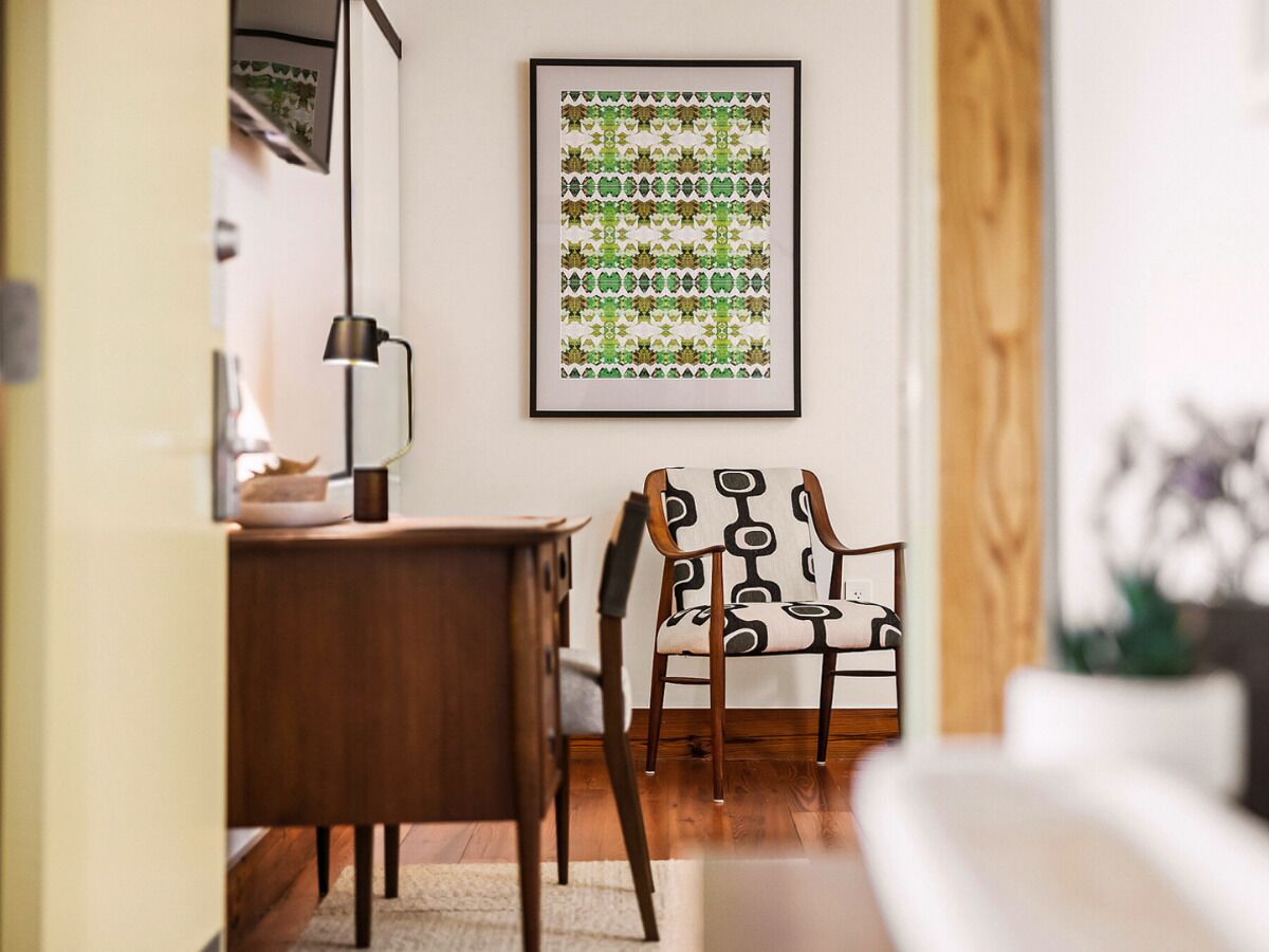 Un coin repas avec une table en bois, une chaise à motifs géométriques et une œuvre d’art encadrée accrochée au mur.