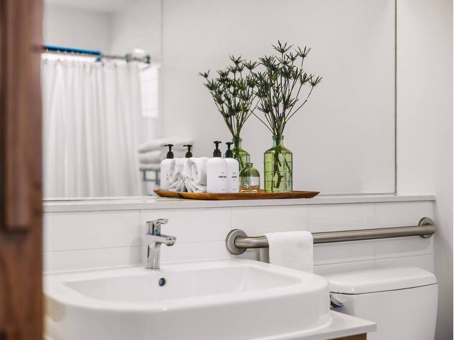 Ein Badezimmer mit Waschbecken, Spiegel und Pflegeprodukten auf einem Regal.