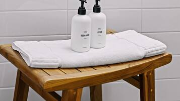Een houten bank met twee witte flesjes, gelabeld 'BODY WASH' en 'LOTION'.