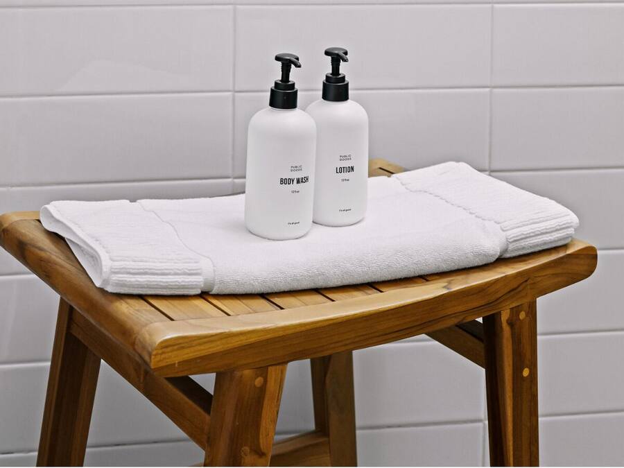 A wooden bench with two white bottles labeled "BODY WASH" and "LOTION" on top.