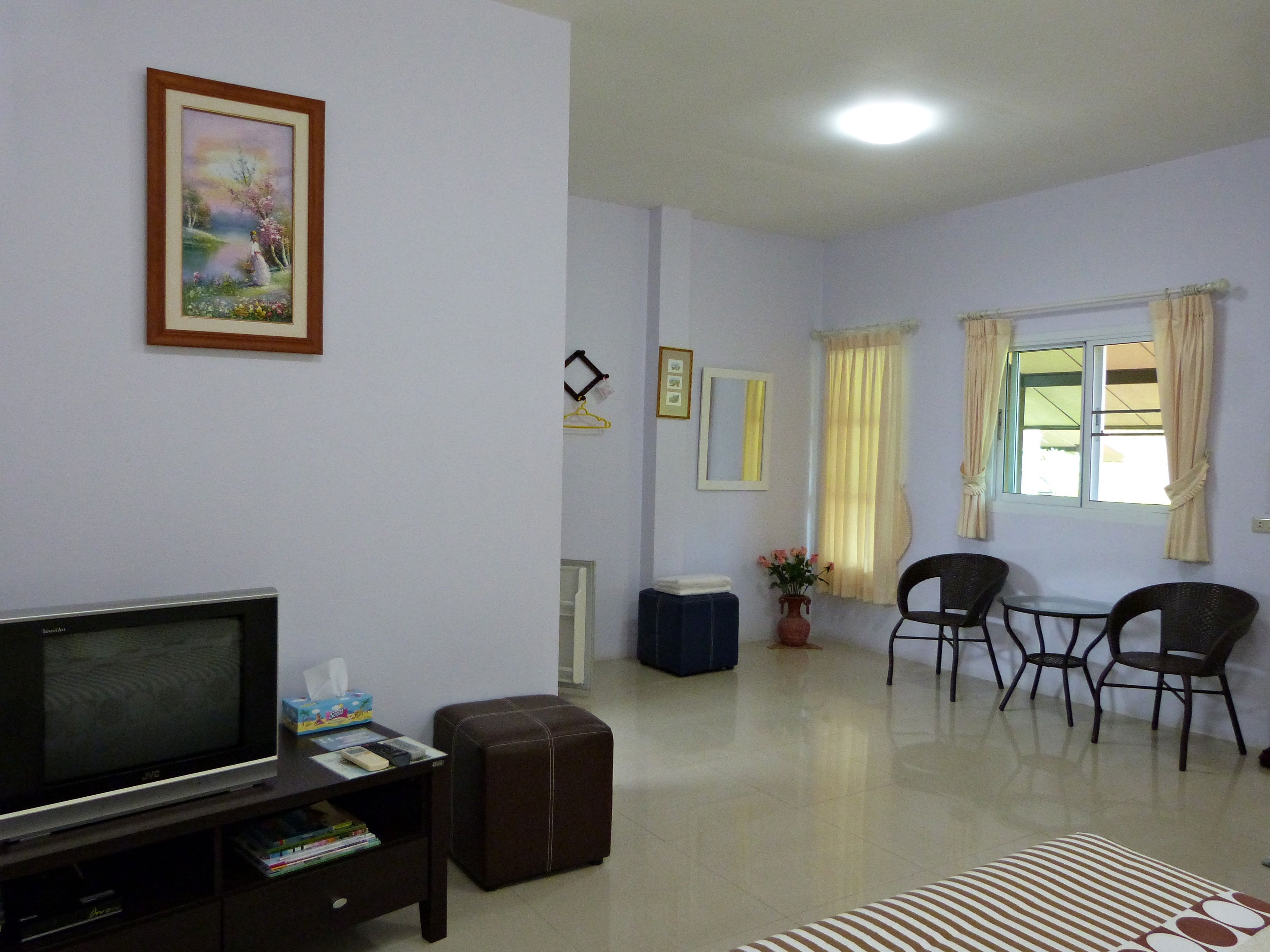 A living room with a TV, a sofa, a coffee table, and a dining area with chairs.