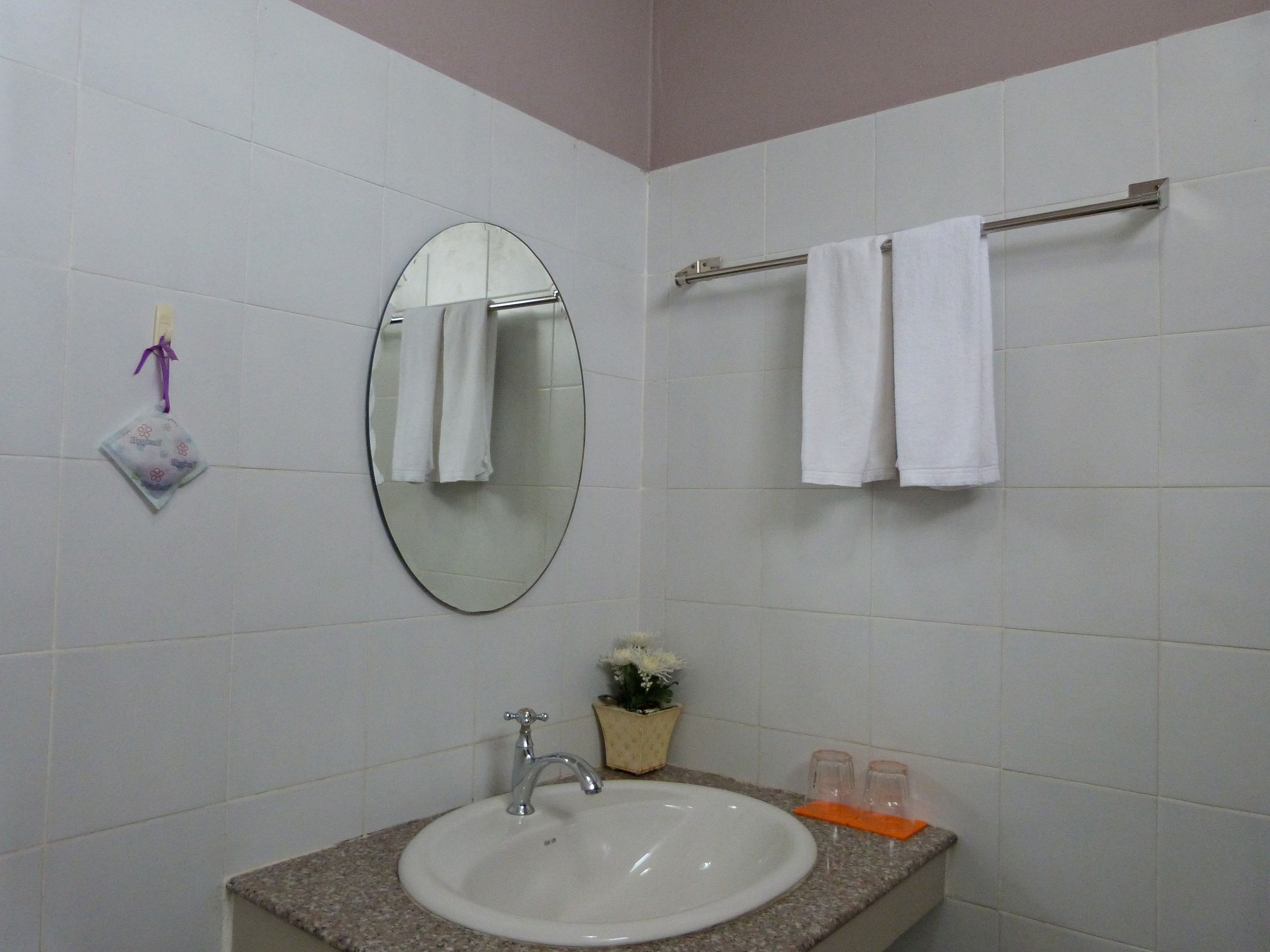 Een badkamer met een wastafel, spiegel, handdoekhouder en een klein decoratief object.