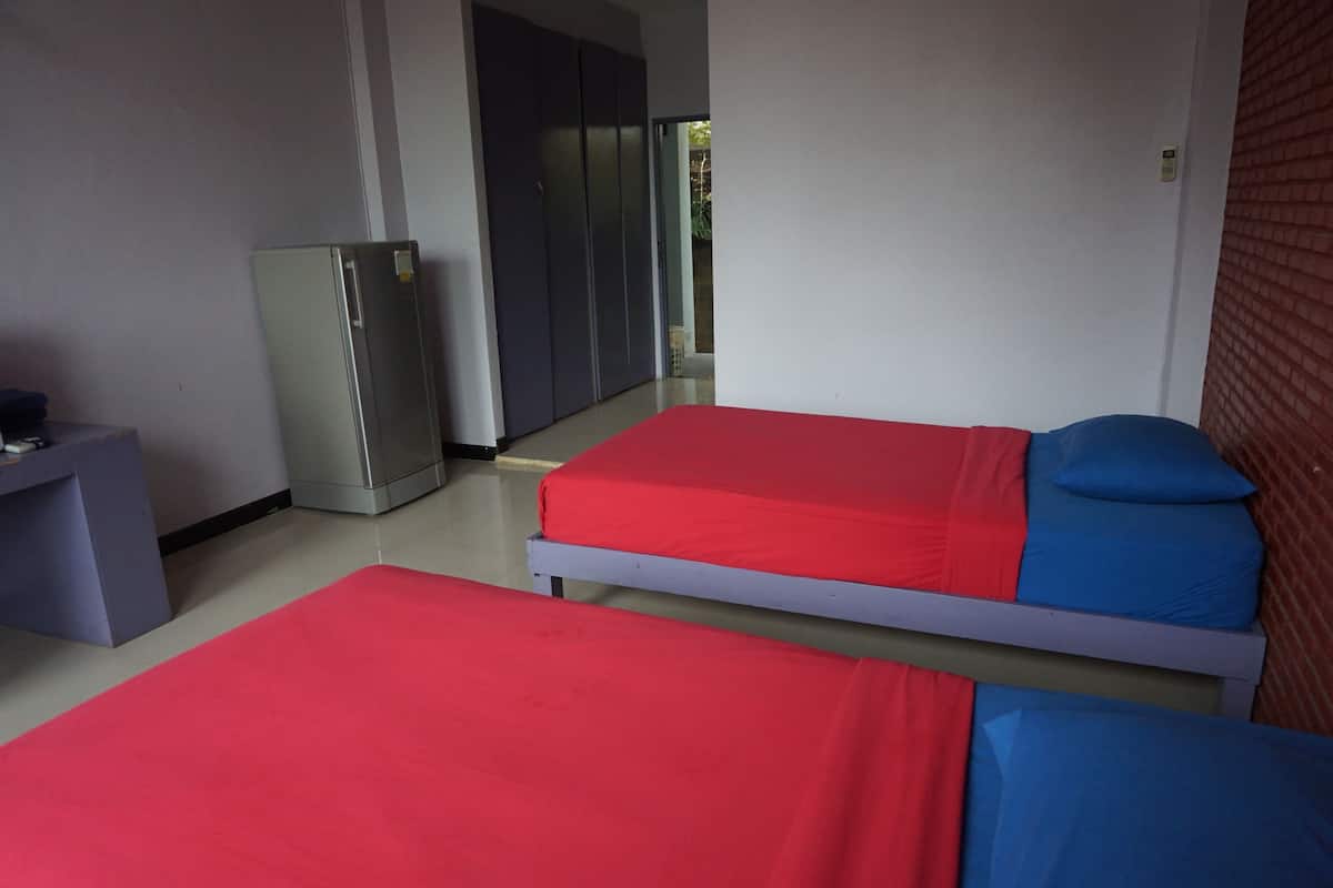 Una habitación con dos camas, un escritorio, un armario y una puerta que da al exterior.