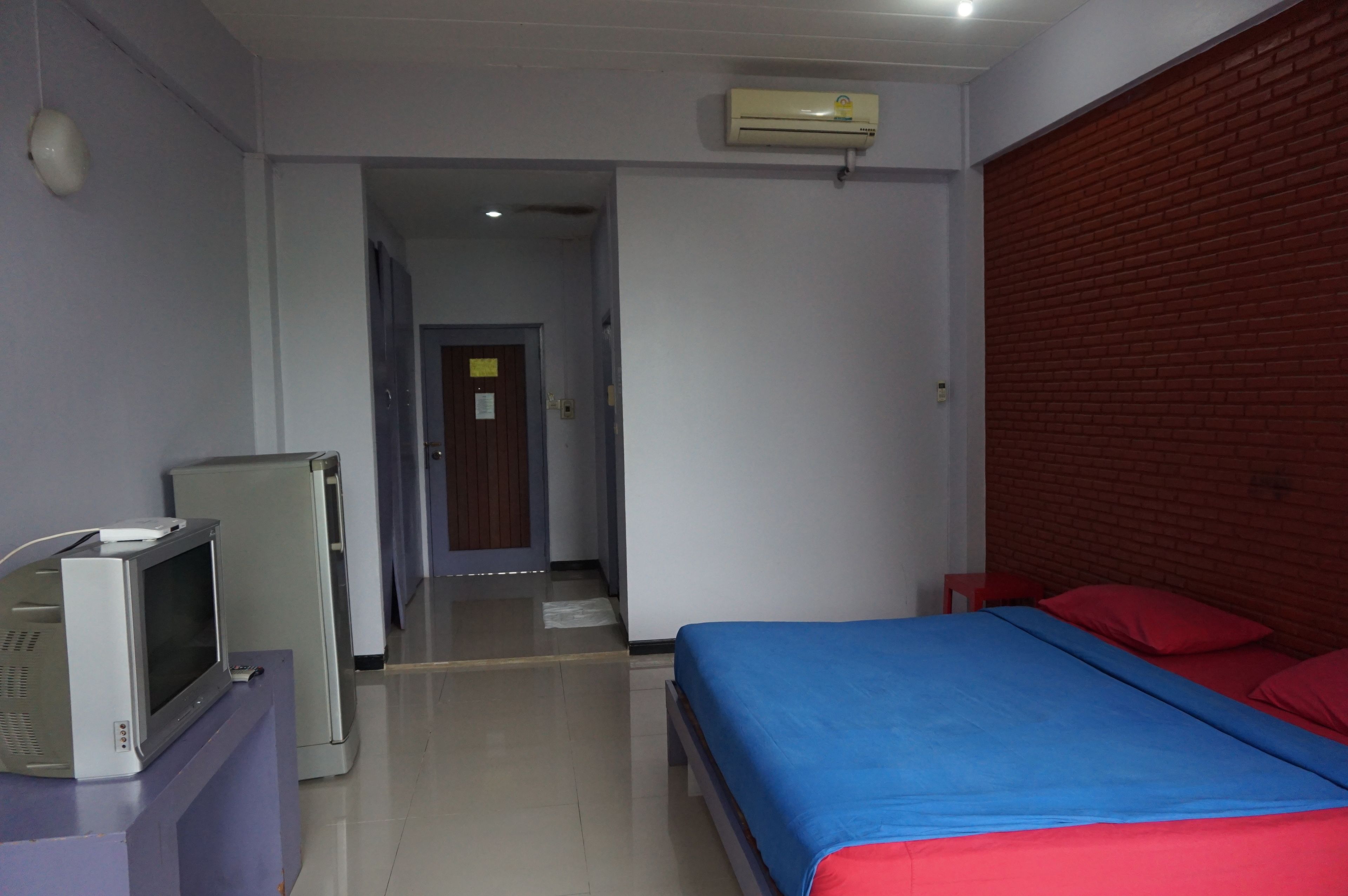 Habitación de hotel con cama, televisor y pared de ladrillo.