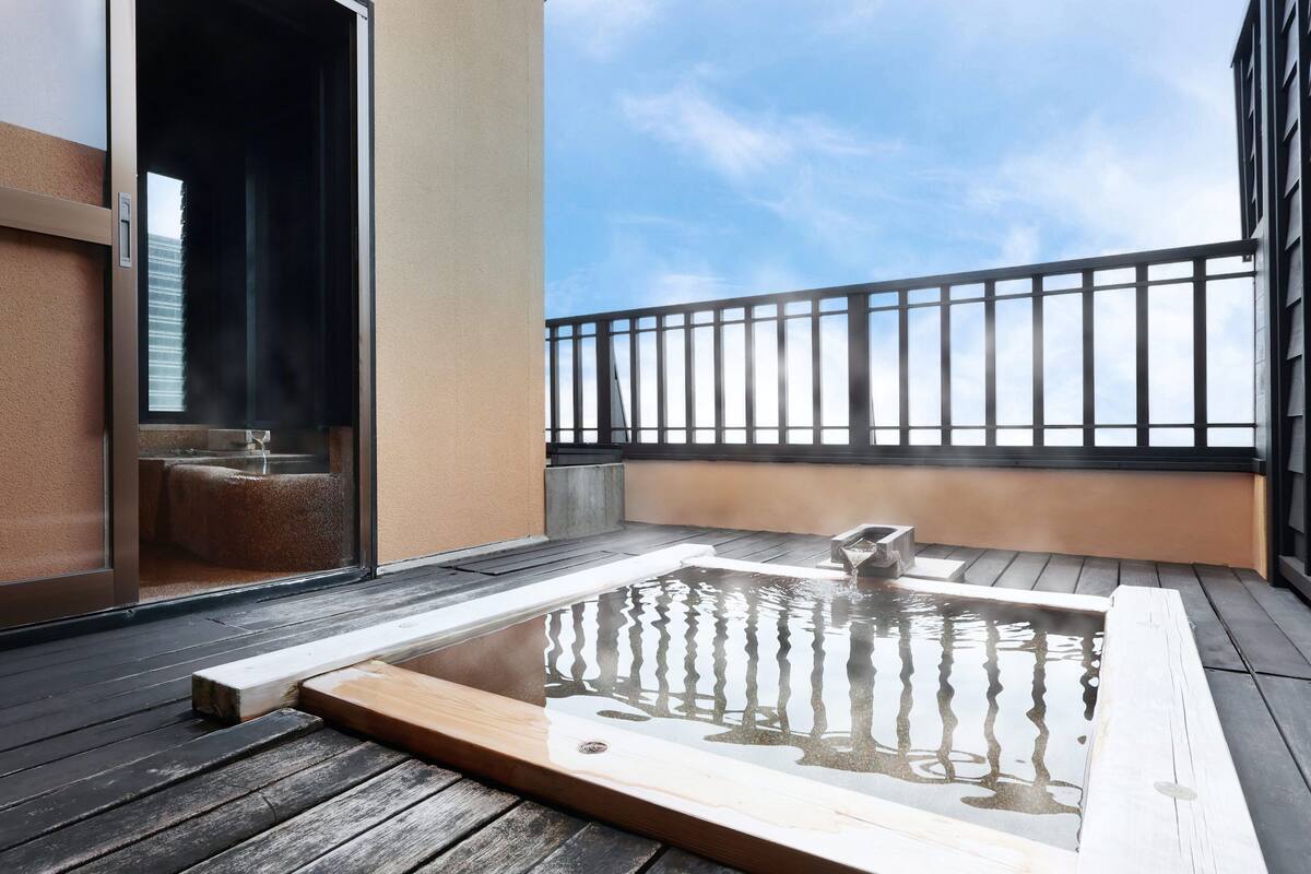 A hot tub on a wooden deck with a view of the sky and a building in the background.
