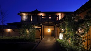 Un edificio japonés tradicional iluminado de noche, con una entrada bien visible y la luna a la vista.