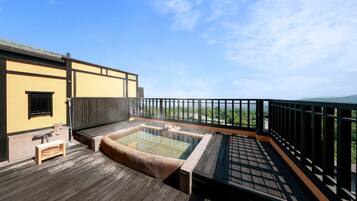 Una terraza de madera con un jacuzzi y un pequeño banco, con vistas a un paisaje verde.