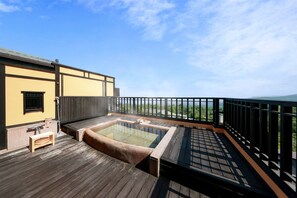 A wooden deck with a hot tub and a small bench, overlooking a green landscape. - Oyado Uchiyama (Ito)