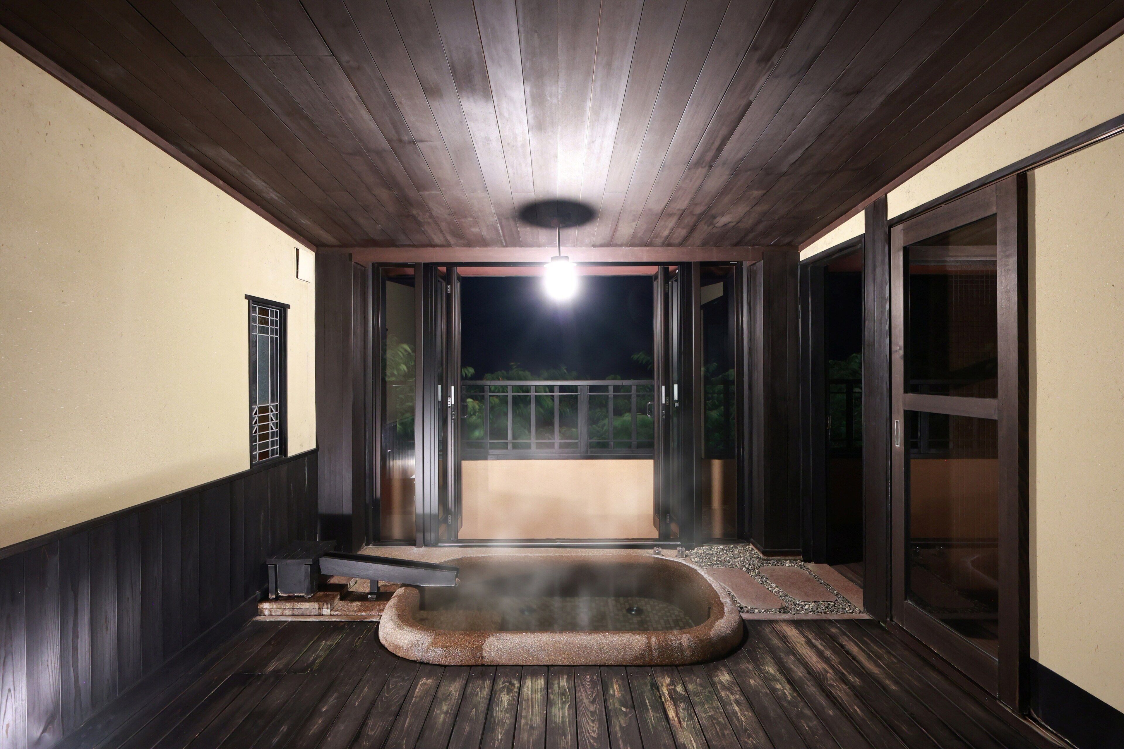 Zona de hidromasaje con terraza de madera, luz en el techo y vistas al exterior.
