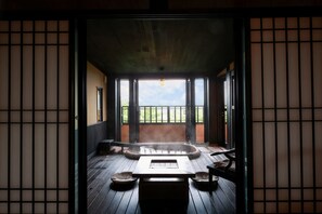 A traditional Japanese onsen with a wooden floor, a hot spring bath, and tatami mats. - Oyado Uchiyama (Ito)