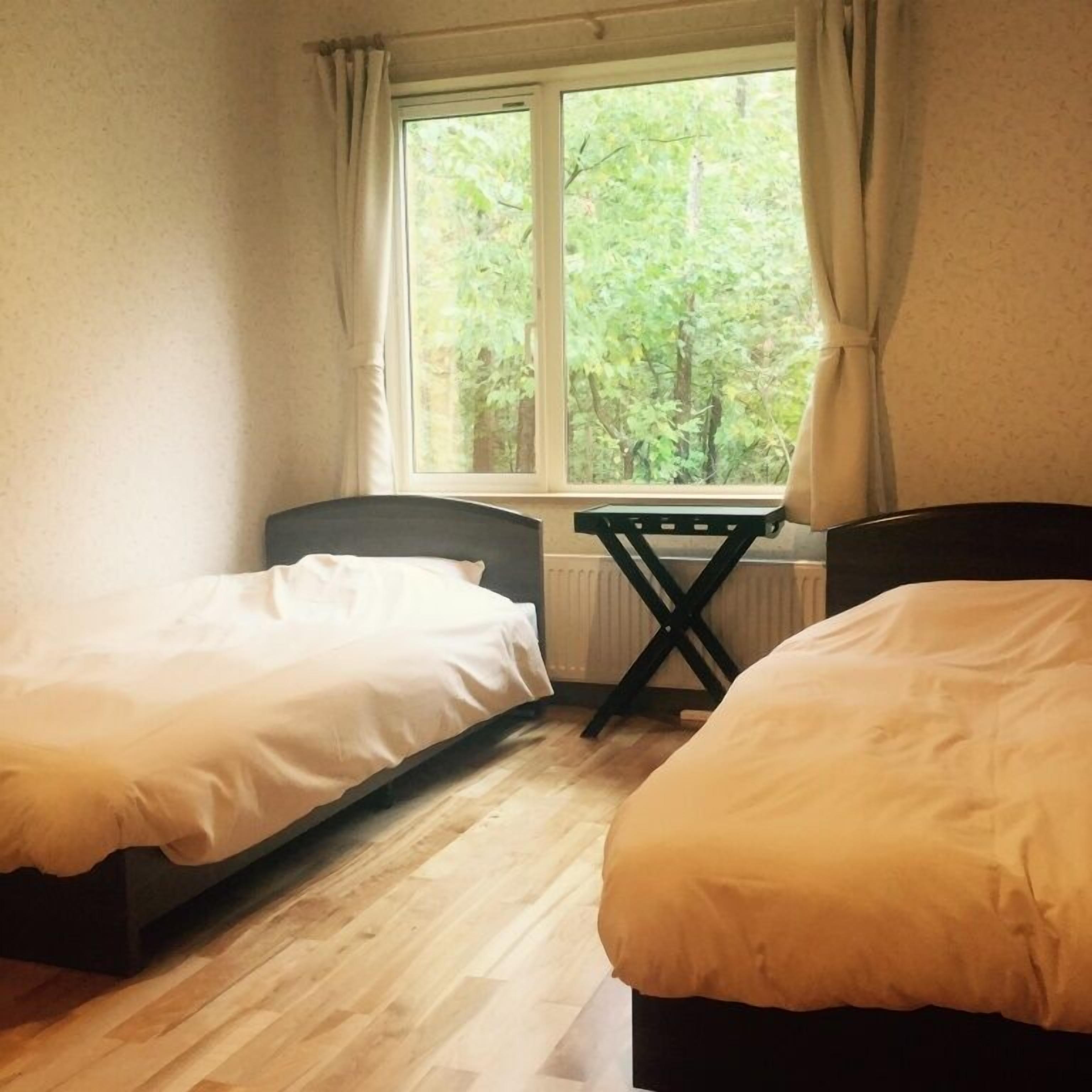Un dormitorio con dos camas, una ventana con cortinas y un radiador.