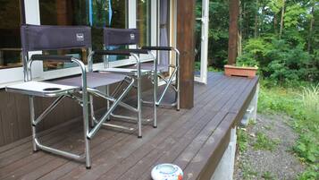 A deck with two chairs and a table, surrounded by a wooden deck and greenery.