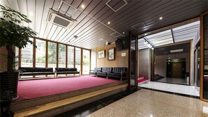A lobby with a red carpeted area, black leather seating, and a large window. - Hotel Arozo (Seoul)