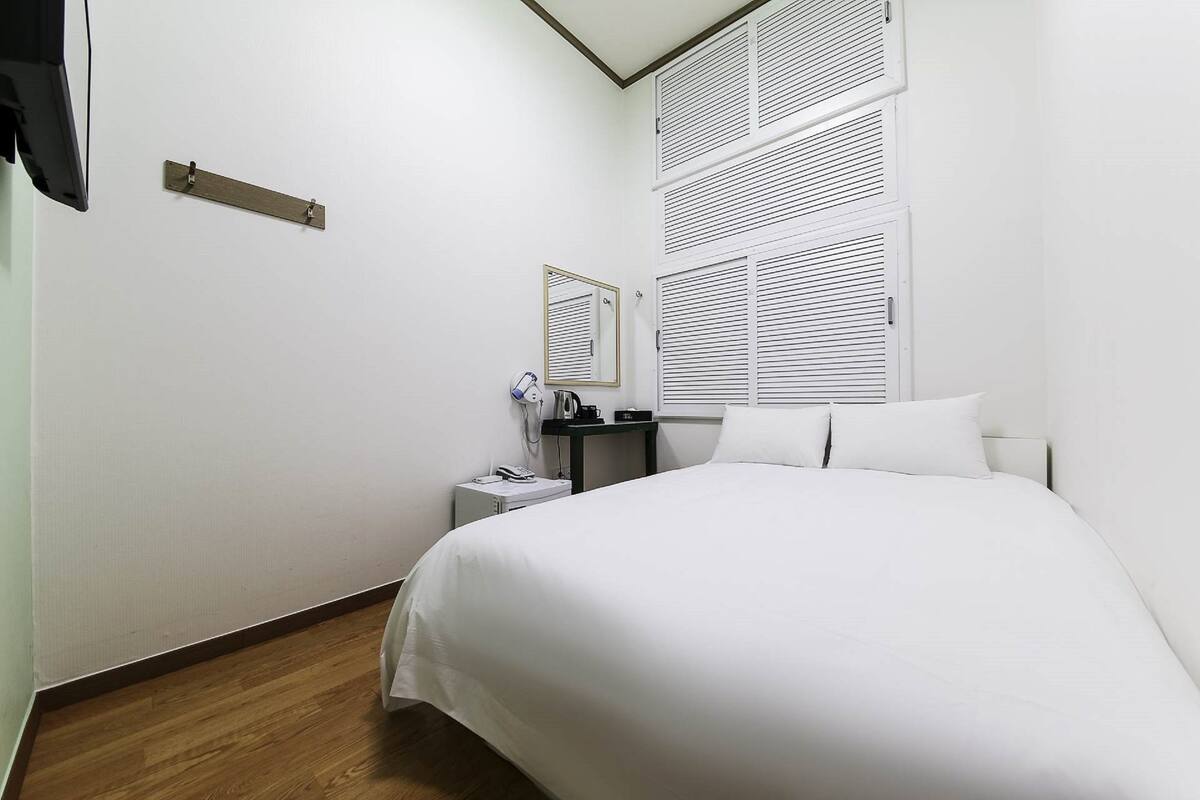 A neatly arranged hotel room with a bed, bedside table, and a mirror.