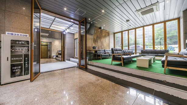 A modern hotel lobby with a reception desk, seating area, and a view of the outdoors. - Hotel Arozo (Seoul)