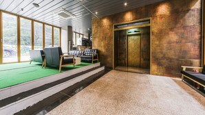 A modern lobby with a green carpeted area, a staircase, and a seating area with leather chairs. - Hotel Arozo (Seoul)