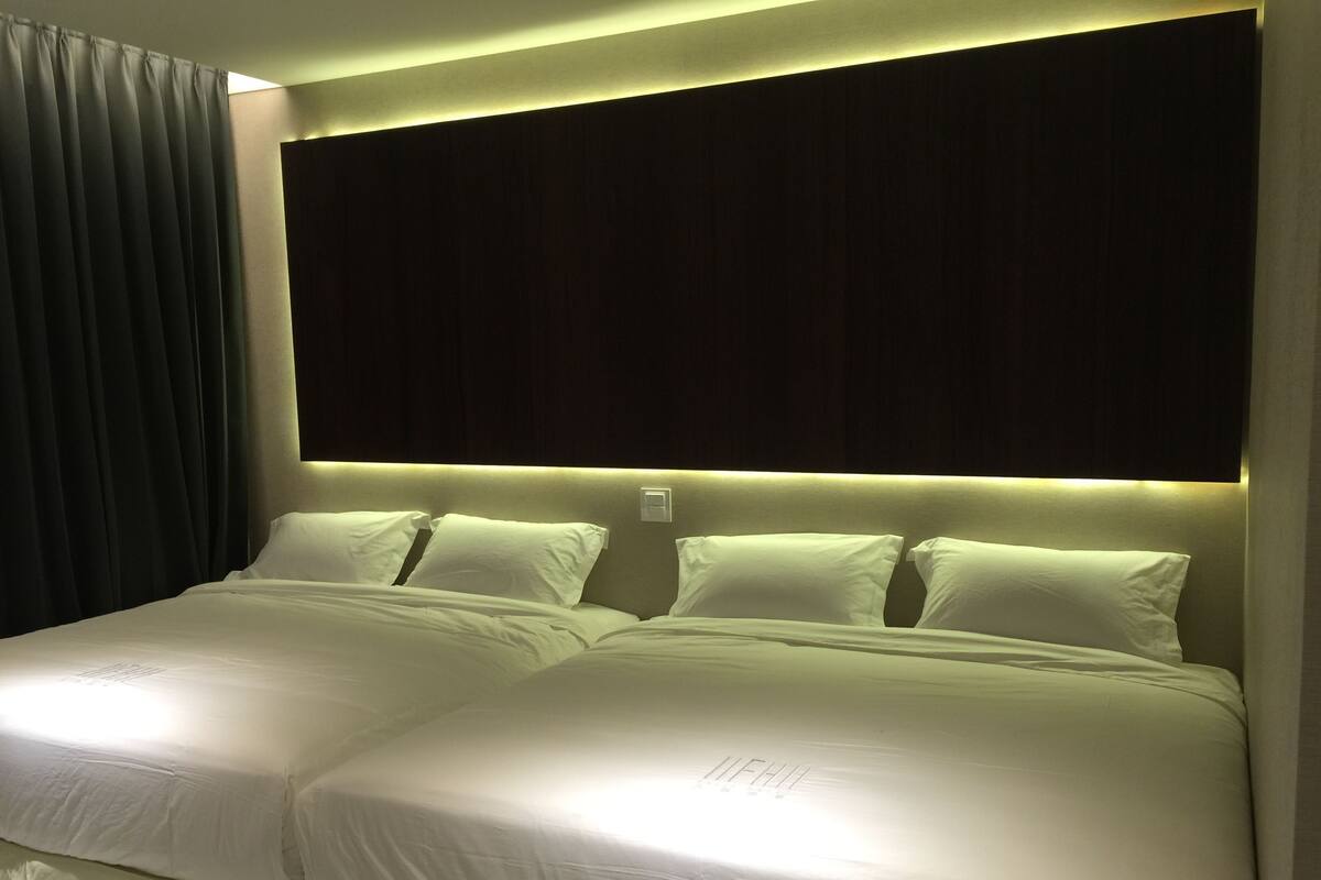 A double bed with a headboard, two pillows, and a bedside table.