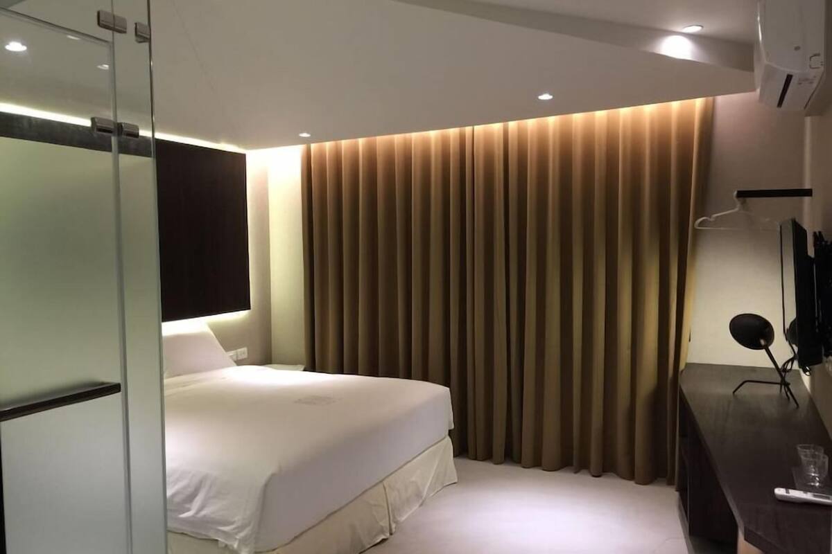 A hotel room with a bed, a desk, and a TV.