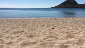 A sandy beach with a clear blue sky and calm water. - Feliz Hotel Kenting (Hengchun)