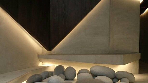 A modern interior with a geometric light installation and a central arrangement of smooth stones. - Feliz Hotel Kenting (Hengchun)