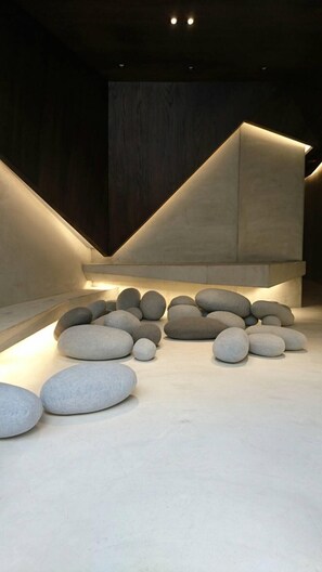 A modern interior with a geometric light installation and a central arrangement of smooth stones. - Feliz Hotel Kenting (Hengchun)