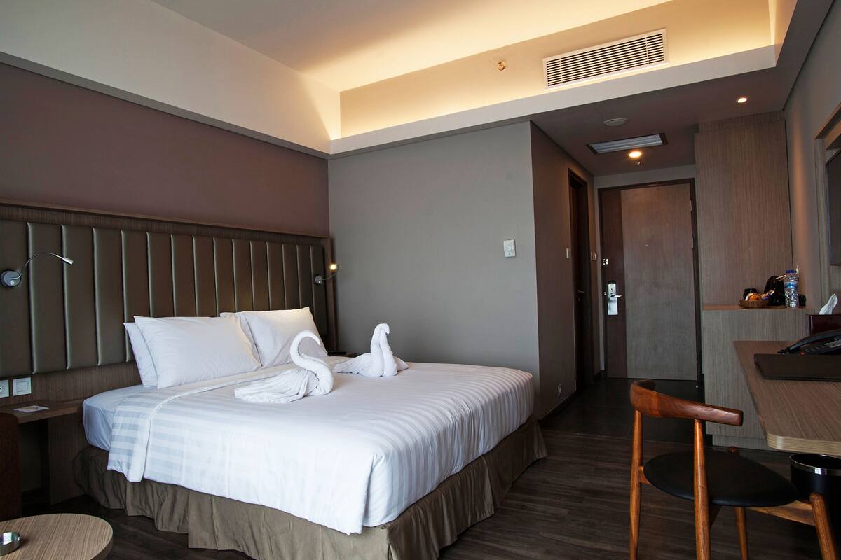 Habitación de hotel con cama, escritorio, silla y puerta.