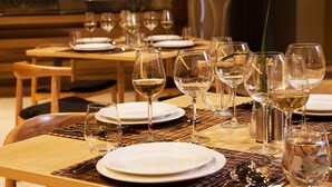 A dining table set with multiple wine glasses and plates, arranged on a woven placemat.