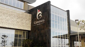 A modern building with a large glass facade, the name "Gammara Hotel" prominently displayed, and a decorative wall with a pattern of holes.
