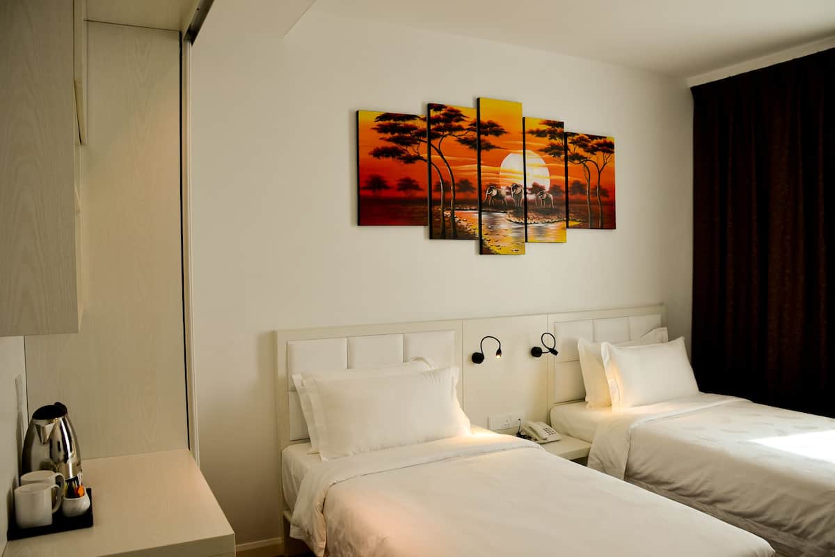 Ein Hotelzimmer mit zwei Betten, einem Sonnenuntergangsbild, einer Kaffeemaschine und einem Telefon auf dem Nachttisch.