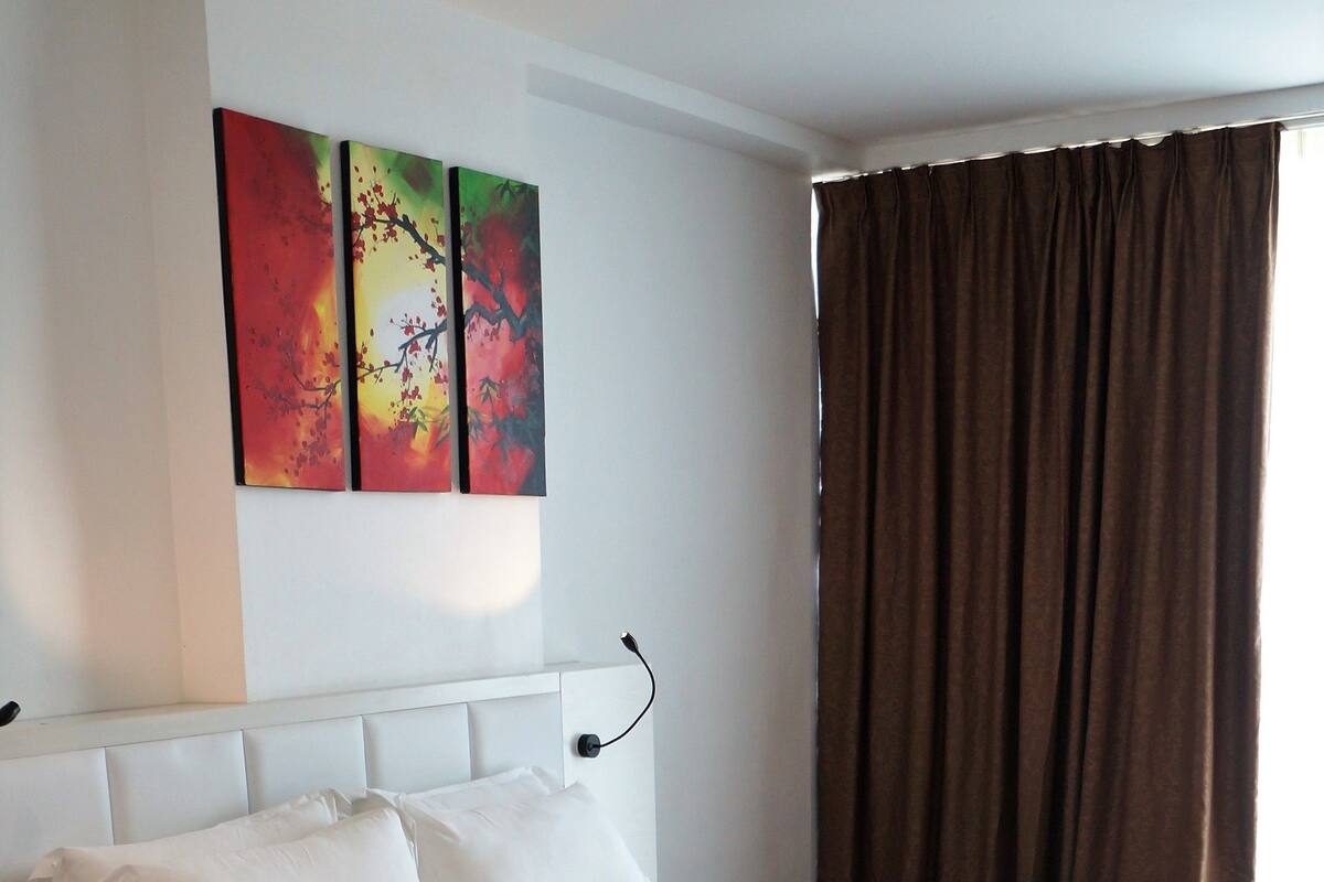 Ein modernes Hotelzimmer mit einem großen Bett, einem Nachttisch und einem an der Wand montierten Fernseher.