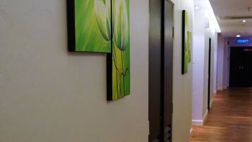 Un pasillo con suelo de madera y arte mural verde que representa formas abstractas.