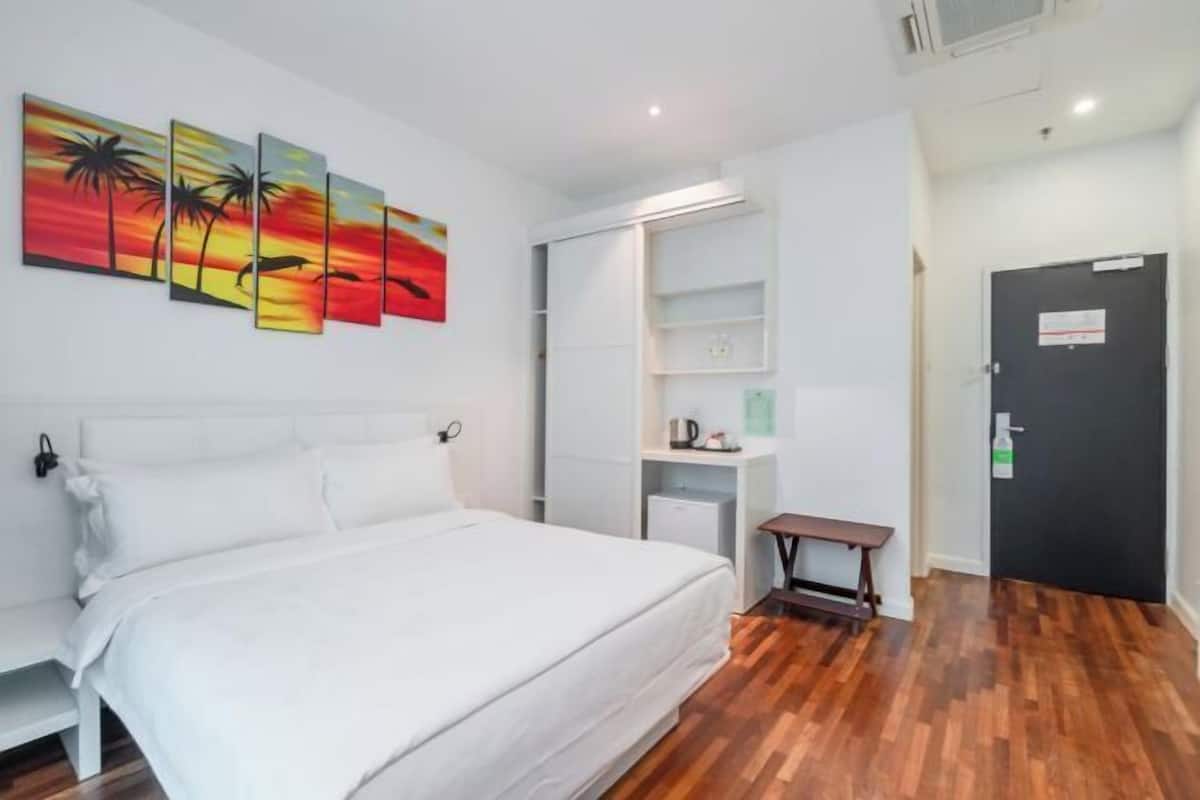 Ein Hotelzimmer mit Bett, einer Sitzbank, einem an der Wand befestigten Regal und einer Tür.