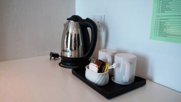 Una cafetera, dos tazas y un recipiente pequeño con bocadillos sobre una bandeja.