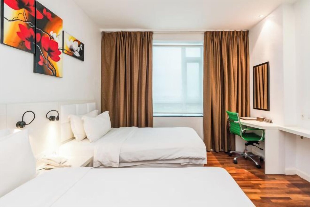Habitación de hotel con cama, escritorio y una silla. Cuenta con una ventana con cortinas, un cuadro en la pared y una lámpara en la mesita de noche.