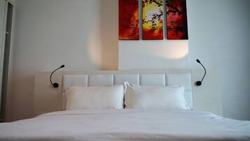 Una cama bien tendida con sábanas blancas en una habitación de hotel.