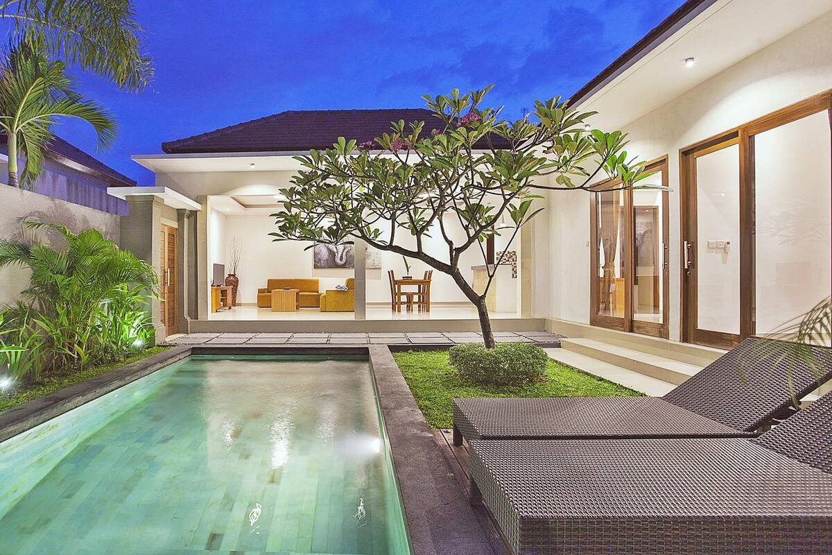 A modern house with a swimming pool, outdoor seating, and a well-maintained garden.