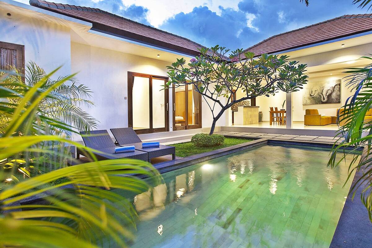 A modern villa with a swimming pool, outdoor seating, and a dining area.