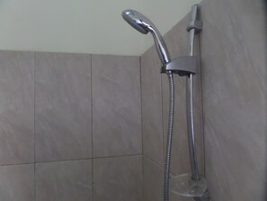 Una ducha con cabezal de ducha de mano y grifo empotrado en la pared.