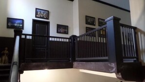 Una escalera con barandilla negra, una estatua y cuadros en las paredes.