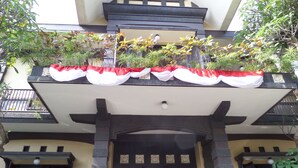 Un edificio de estilo arquitectónico tradicional, con un balcón adornado con macetas y un toldo decorativo.