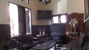 Una habitación con piso a cuadros, un conjunto de sofás, una mesa y un televisor montado en la pared.