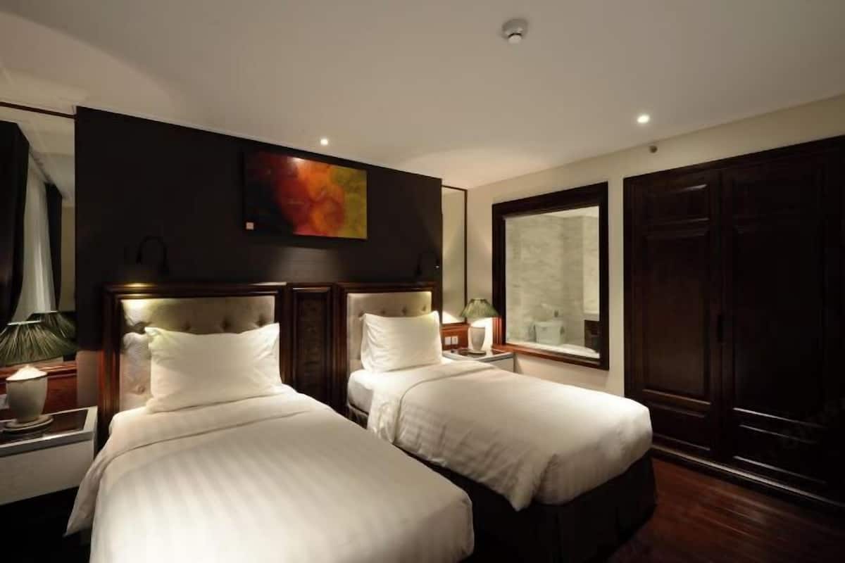 Une chambre d’hôtel avec deux lits, une grande fenêtre et un tableau au mur.