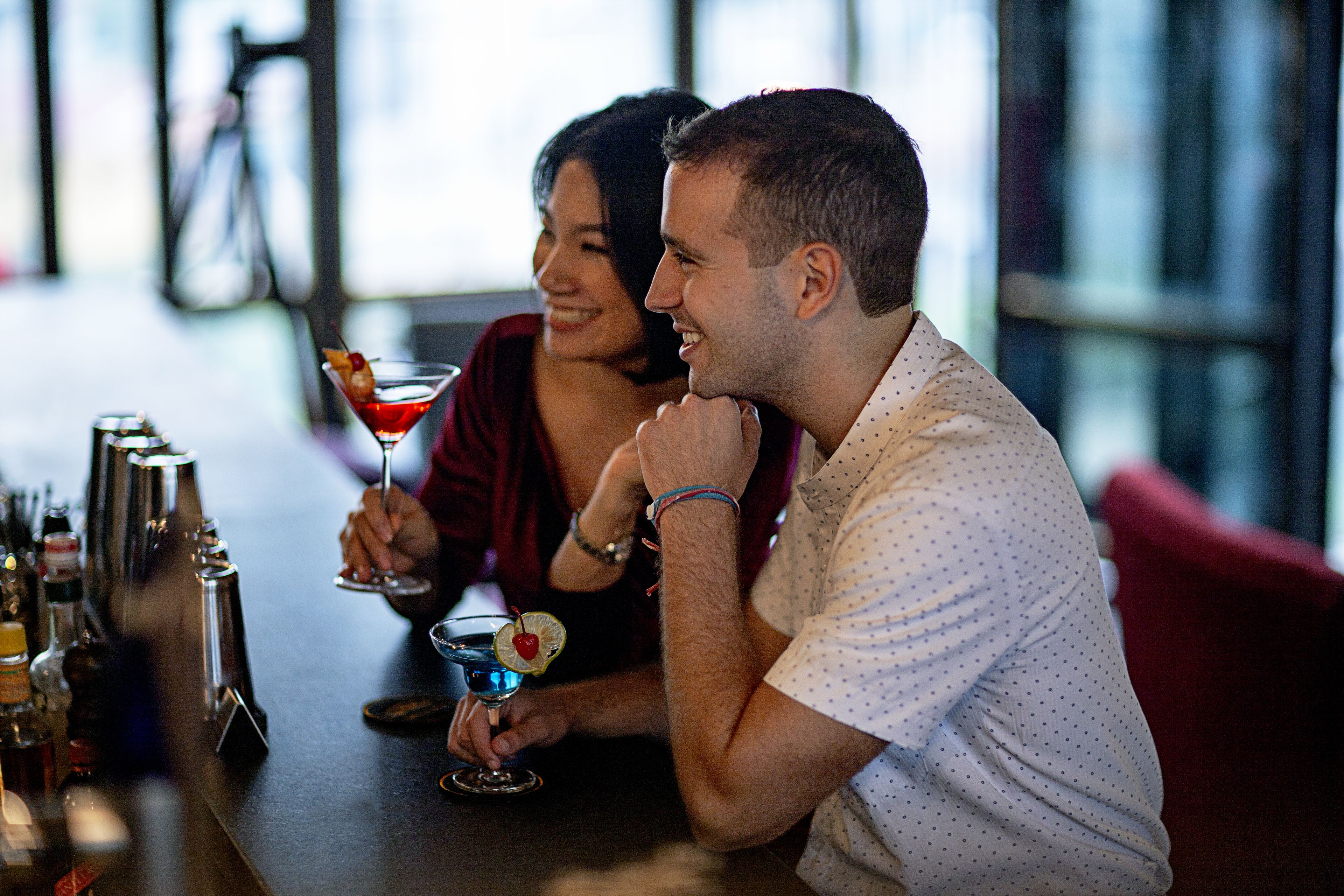 Two people seated at a bar with a drink in front of them.