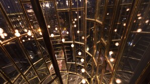 Un escalier en colimaçon avec des rampes en verre et de nombreux luminaires.